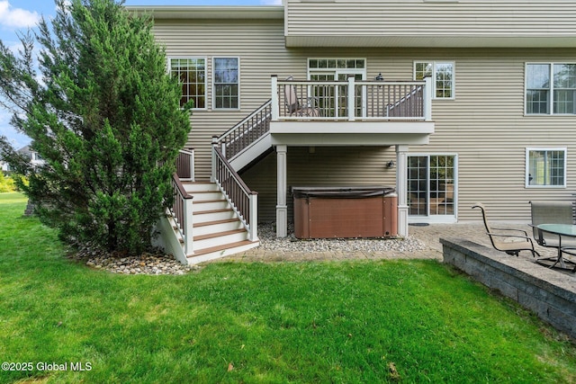 back of property with a yard, a hot tub, and a patio