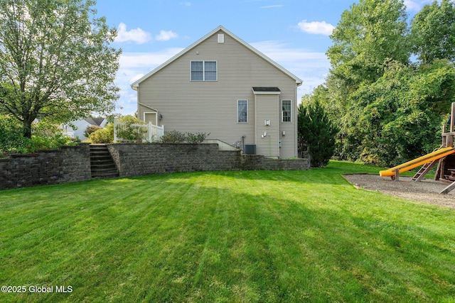 rear view of property with a playground, a yard, and cooling unit