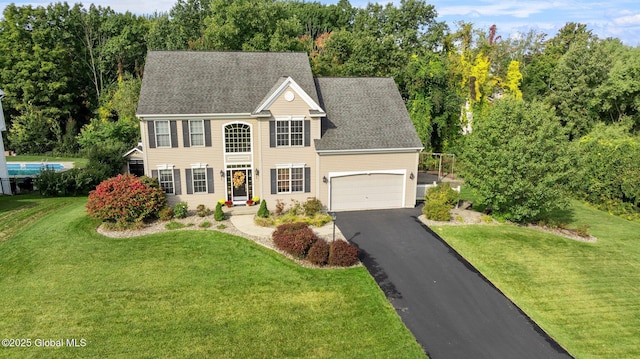 colonial home featuring a garage and a front lawn