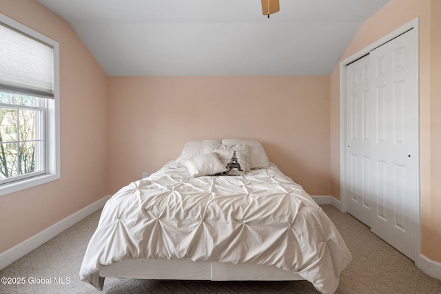 bedroom with lofted ceiling, light carpet, ceiling fan, and a closet