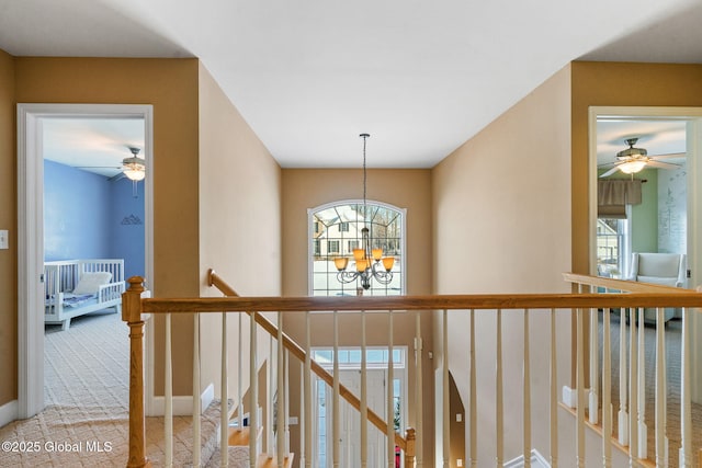 corridor with a notable chandelier and light colored carpet