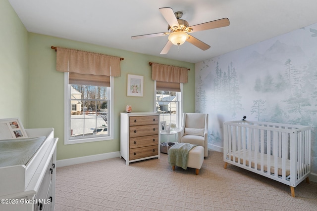 bedroom with a crib, light carpet, and ceiling fan