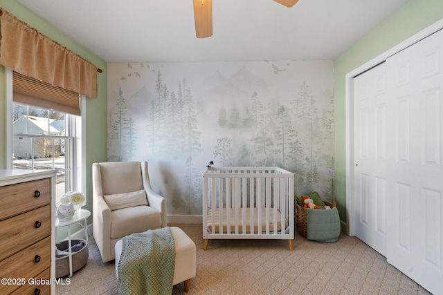 bedroom with ceiling fan, a closet, and a crib