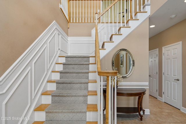 stairway featuring tile patterned flooring and a towering ceiling