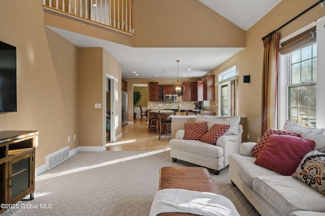 carpeted living room with high vaulted ceiling