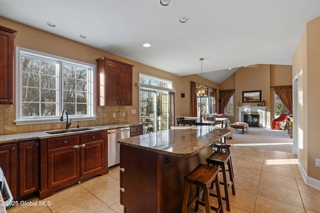 kitchen with sink, hanging light fixtures, a kitchen breakfast bar, a center island, and tasteful backsplash