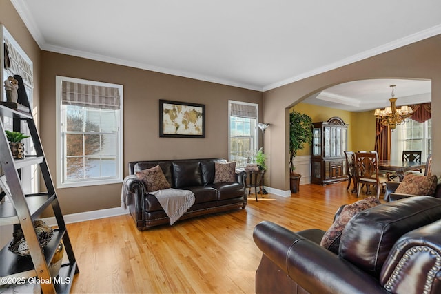 living room featuring a notable chandelier, crown molding, plenty of natural light, and light hardwood / wood-style floors