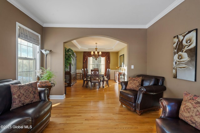 living room with an inviting chandelier, a tray ceiling, light hardwood / wood-style floors, and crown molding