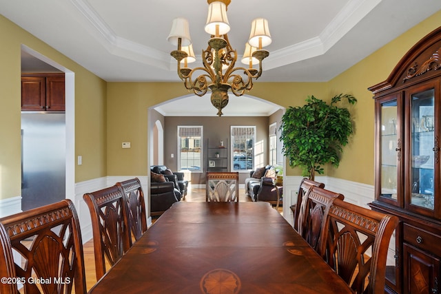 dining space featuring a raised ceiling, ornamental molding, and an inviting chandelier