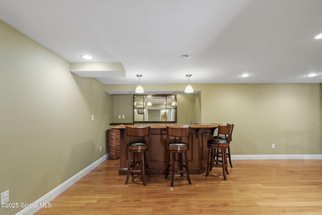 bar with pendant lighting, sink, and light wood-type flooring