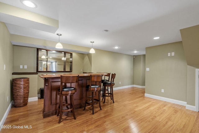 bar with decorative light fixtures and light hardwood / wood-style flooring