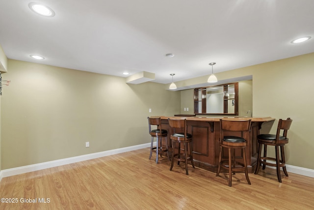 bar with light wood-type flooring and decorative light fixtures