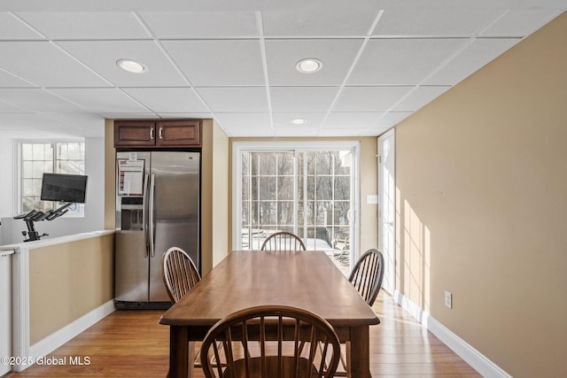 dining area featuring a drop ceiling and light hardwood / wood-style flooring