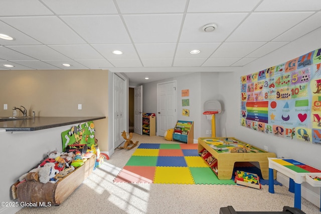 game room featuring light carpet, sink, and a drop ceiling