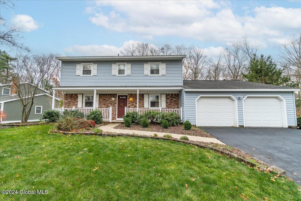 front facade featuring a porch, a garage, and a front yard