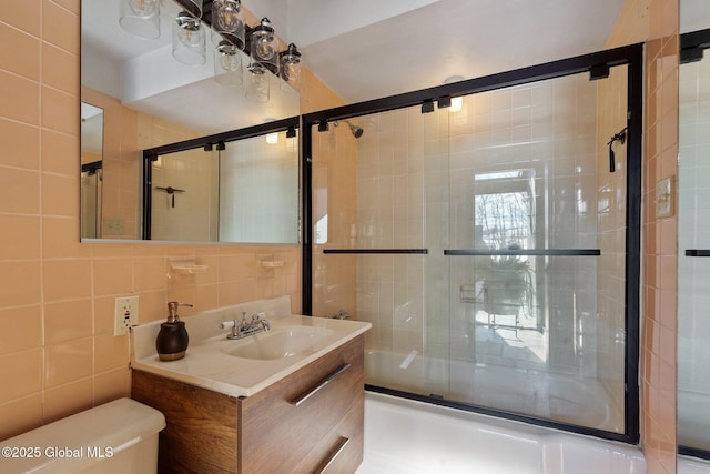 full bathroom with enclosed tub / shower combo, tile walls, backsplash, vanity, and toilet