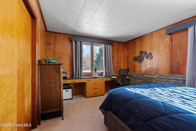 bedroom with light colored carpet, wooden walls, built in desk, and a closet