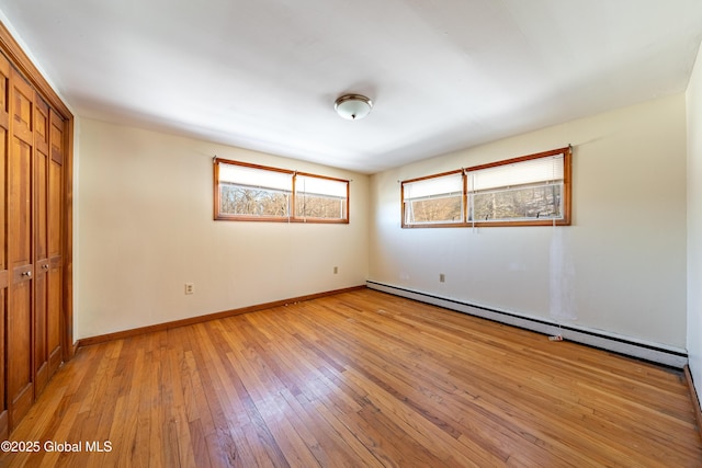 unfurnished bedroom with light hardwood / wood-style flooring, a closet, and baseboard heating