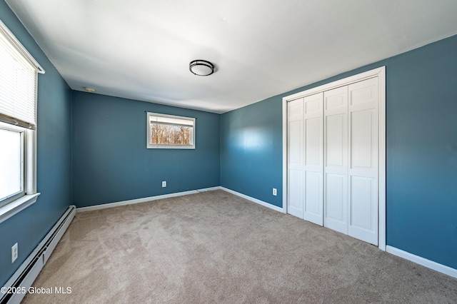 unfurnished bedroom with multiple windows, light colored carpet, baseboard heating, and a closet