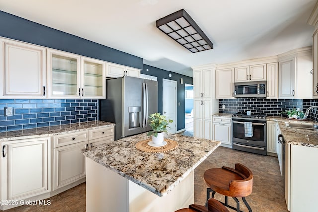 kitchen featuring sink, a breakfast bar area, stainless steel appliances, light stone countertops, and a kitchen island