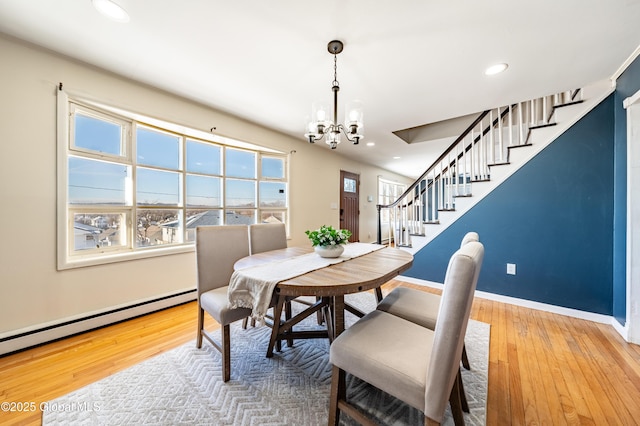 dining area with hardwood / wood-style flooring, a baseboard radiator, plenty of natural light, and a chandelier