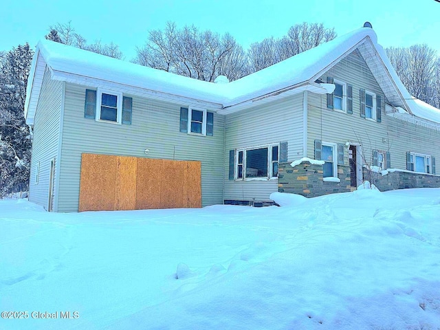 snow covered rear of property featuring a garage