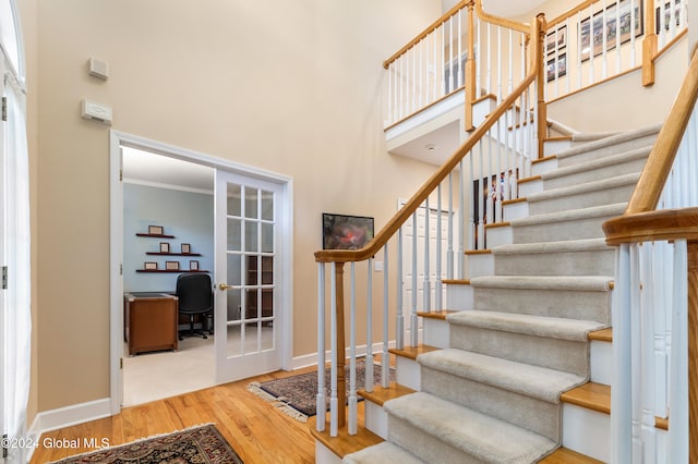 staircase featuring hardwood / wood-style flooring, ornamental molding, and french doors