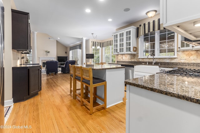 kitchen featuring vaulted ceiling, a kitchen island, decorative columns, white cabinets, and light hardwood / wood-style flooring