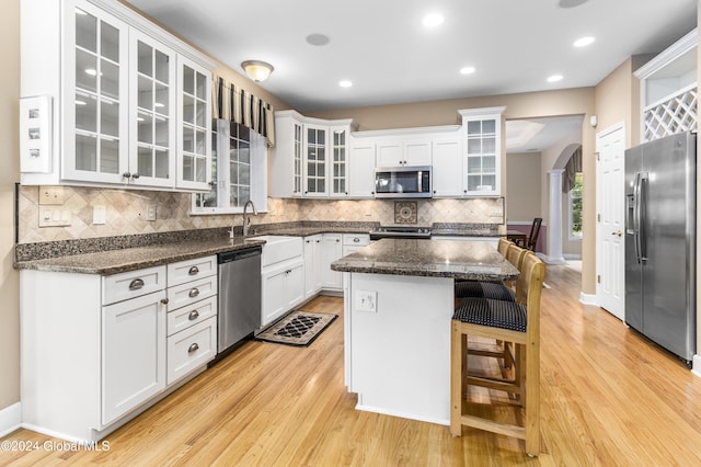 kitchen featuring sink, stainless steel appliances, light hardwood / wood-style floors, white cabinets, and a kitchen island