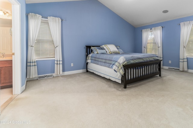 bedroom with light carpet, connected bathroom, vaulted ceiling, and sink