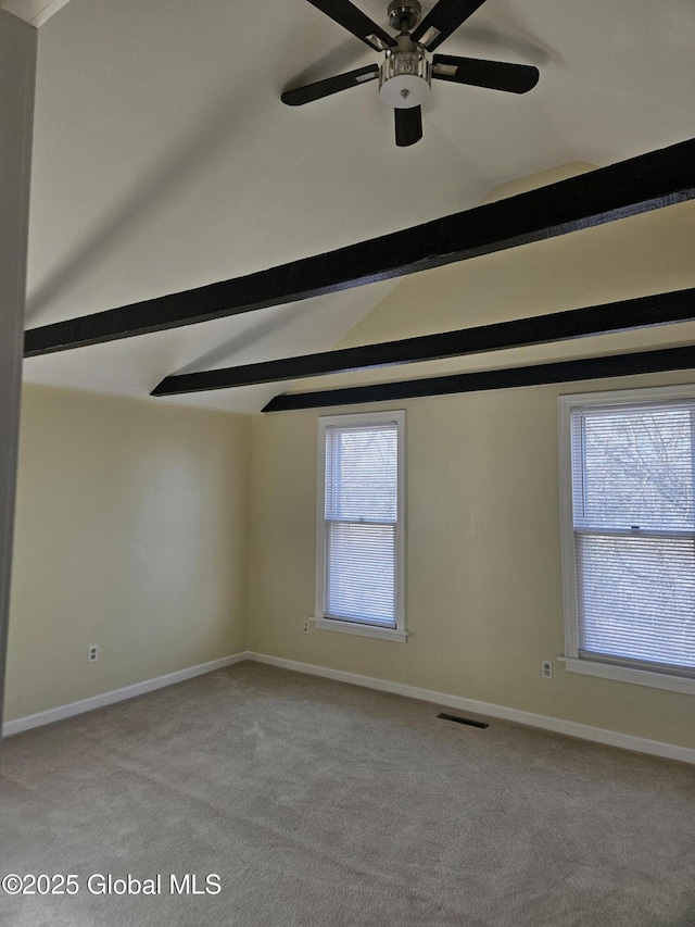 carpeted spare room featuring ceiling fan, lofted ceiling with beams, and a wealth of natural light