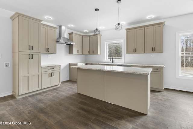 kitchen with wall chimney range hood, a center island, a healthy amount of sunlight, and pendant lighting