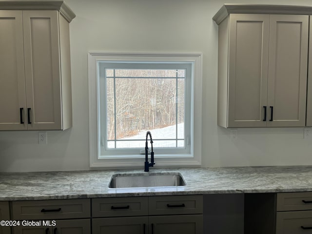 kitchen with sink, gray cabinets, and light stone countertops