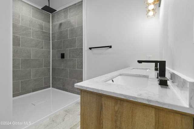 bathroom with a tile shower and vanity