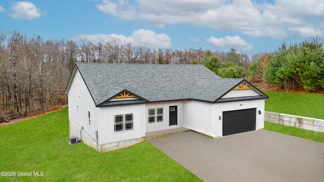 view of front of property featuring a front yard, a garage, and central AC unit