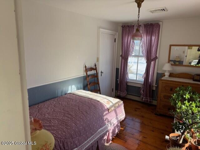 bedroom with baseboard heating and dark hardwood / wood-style flooring