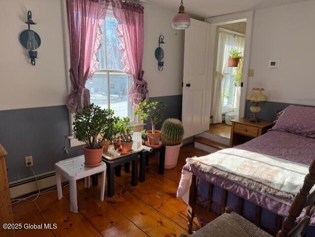 bedroom with a baseboard heating unit and hardwood / wood-style floors