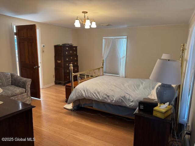 bedroom featuring a notable chandelier, crown molding, and light hardwood / wood-style flooring