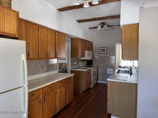 kitchen with sink, white appliances, ceiling fan, dark wood-type flooring, and beam ceiling