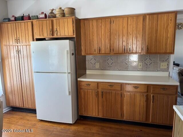 kitchen with white refrigerator, hardwood / wood-style floors, and backsplash