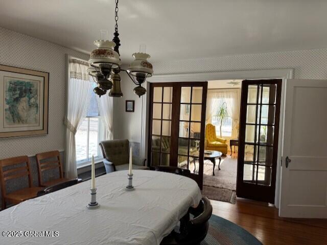 dining area with french doors, an inviting chandelier, and dark wood-type flooring