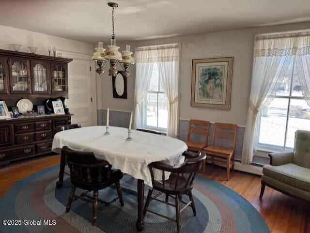 dining space with an inviting chandelier, dark wood-type flooring, and a healthy amount of sunlight