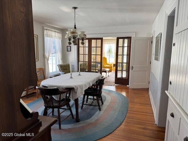 dining area with a baseboard heating unit, hardwood / wood-style flooring, french doors, and a chandelier