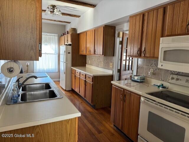 kitchen featuring beam ceiling, tasteful backsplash, sink, and white appliances