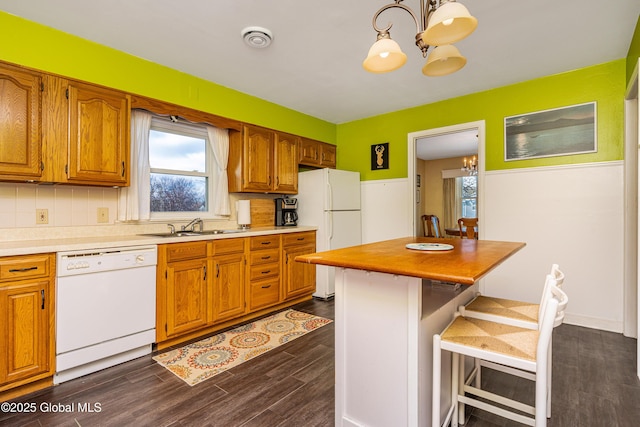 kitchen featuring an inviting chandelier, white appliances, decorative light fixtures, and a breakfast bar