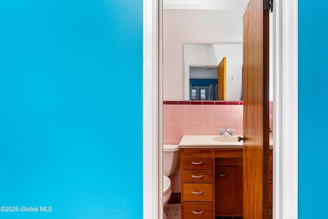 bathroom featuring vanity, tile walls, and toilet