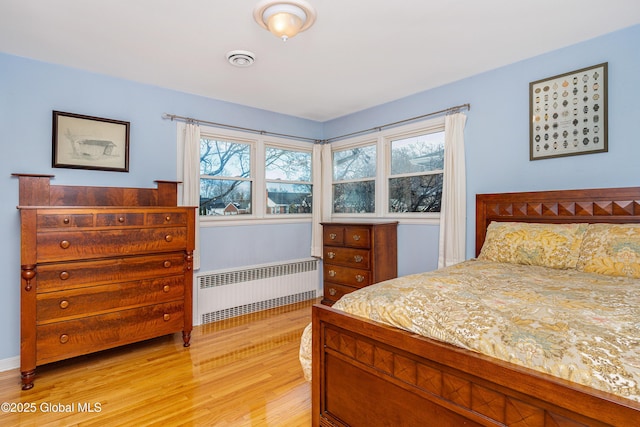 bedroom featuring radiator heating unit and light hardwood / wood-style flooring