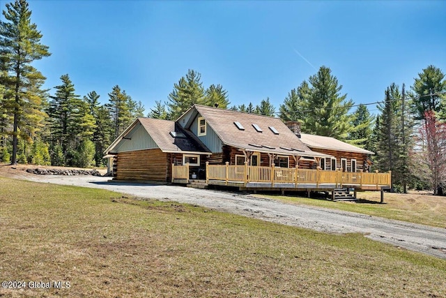 log home featuring a wooden deck and a front lawn