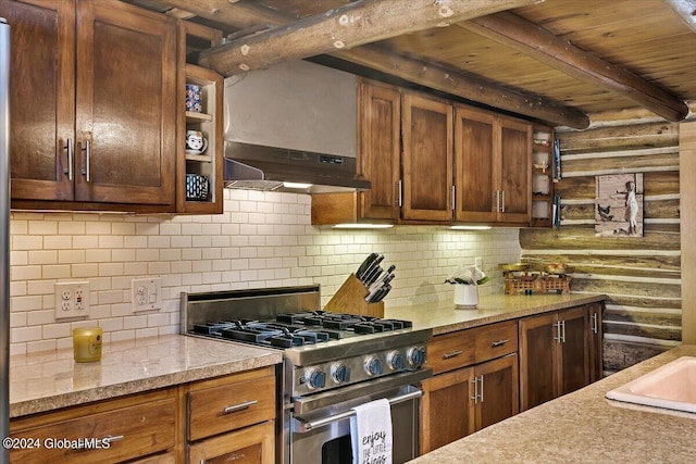 kitchen with beam ceiling, gas range, decorative backsplash, and rustic walls