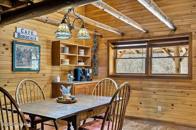 dining area with beam ceiling, hardwood / wood-style floors, wood ceiling, and wooden walls